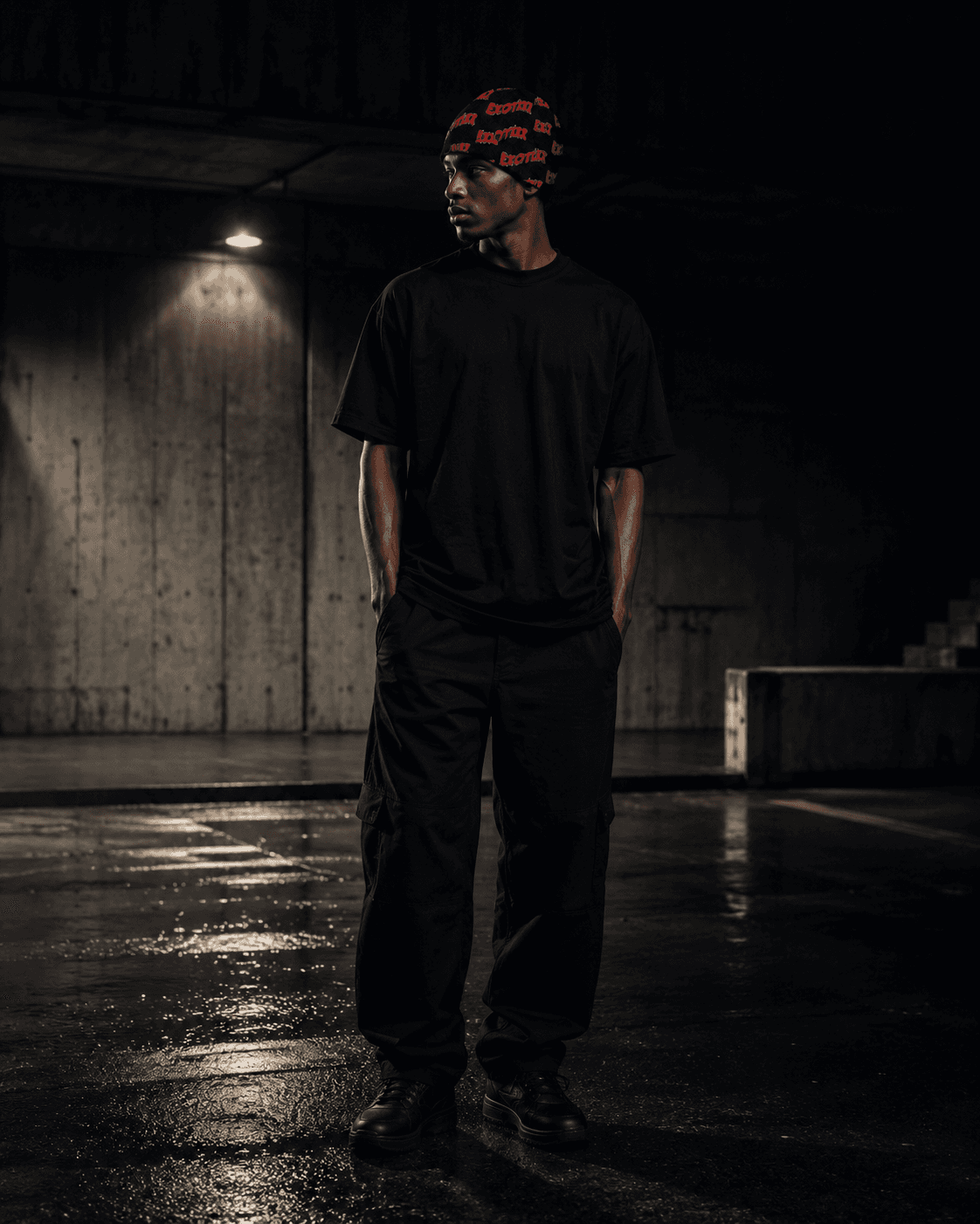 Model in a red Mr. Exotixx knit beanie and full black fit under directional overhead light